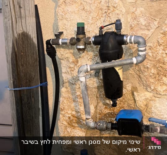 צנרת מים עם ברזים ומסנן על קיר אבן